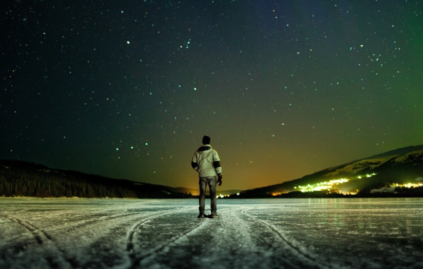 Мужчина на льду смотрит на звезды