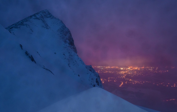 Заснеженная скала на фоне ночного города