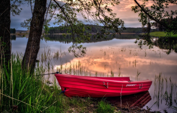 Красная лодка на берегу водоема