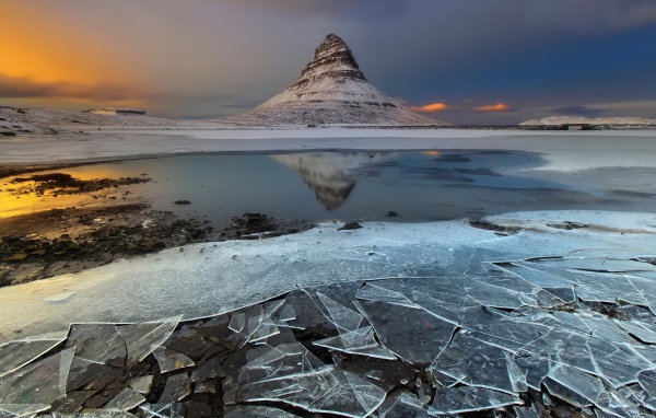 Тонкий лед озера на фоне горы