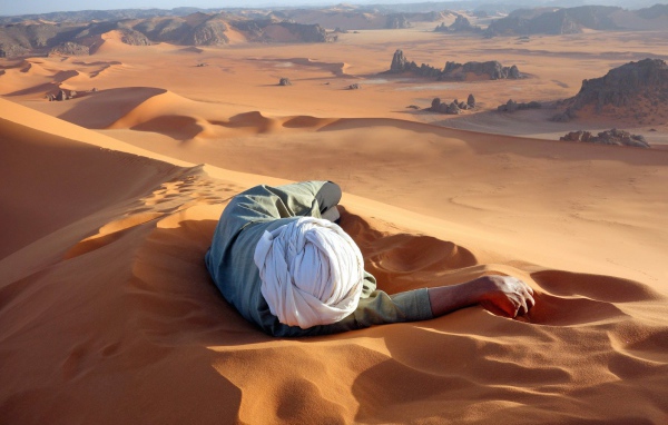 Человек лежит на песке в пустыне