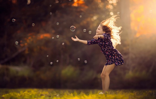 Девочка играет с мыльными пузырями