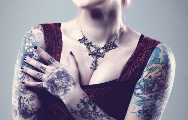 Красивый кулон на груди татуированной девушки