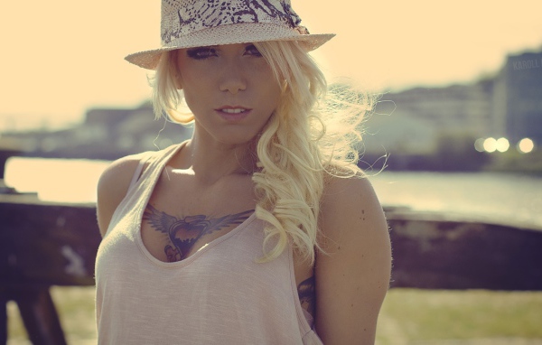 Блондинка в белой шляпе с тату на груди