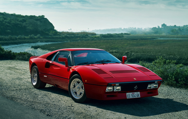 Красный быстрый автомобиль Ferrari 288 GTO у реки