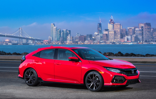Красный автомобиль Honda Civic Touring Hatchback, 2017 на фоне города 