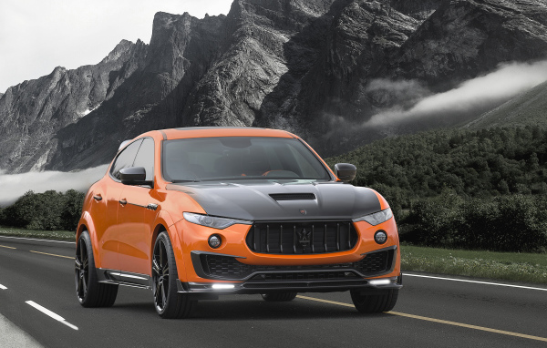 Оранжевый автомобиль Maserati Mansory Levante, 2017 на фоне гор
