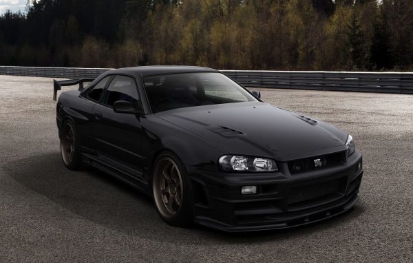Черный автомобиль Nissan Skyline GT-R R34 на трассе