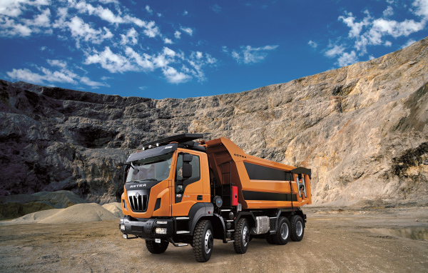 Оранжевый грузовик Astra HD9 84.50 8×4 в карьере под голубым небом