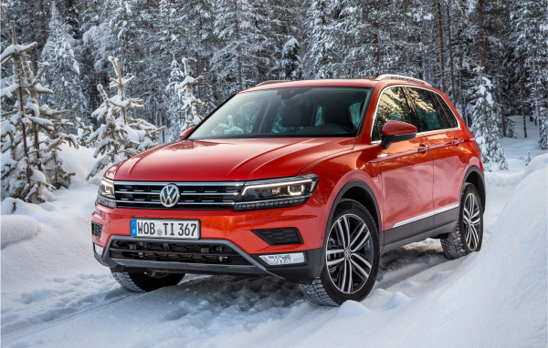 Красный Volkswagen Tiguan 2017 года в заснеженном лесу 
