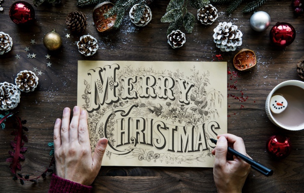 Рисунок с надписью Merry Christmas на столе с новогодними украшениями