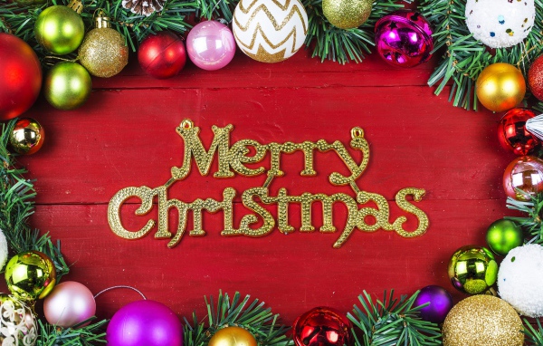 Надпись Merry Christmas на красном фоне с елочными игрушками на Рождество