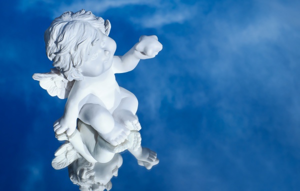 Маленькая статуя купидона отражается в голубой поверхности