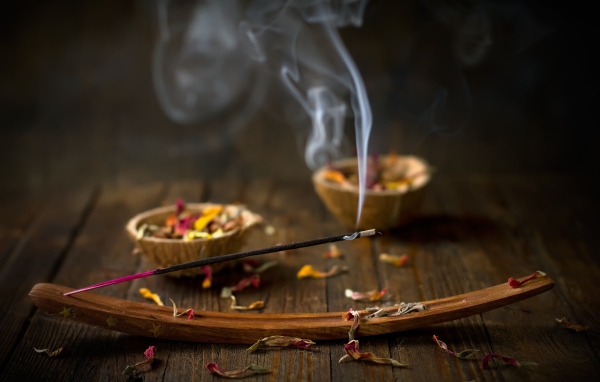 Ароматическая палочка на столе с сухими лепестками цветов