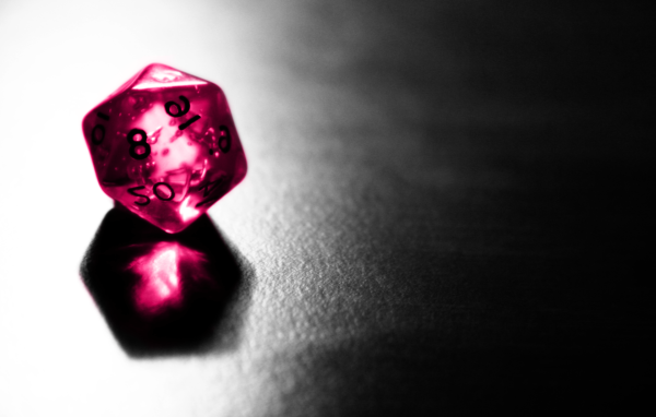 Розовый фигурный кубик отражается серой поверхности стола