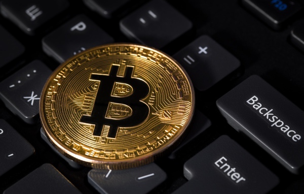 Монета биткоин лежит на черной клавиатуре