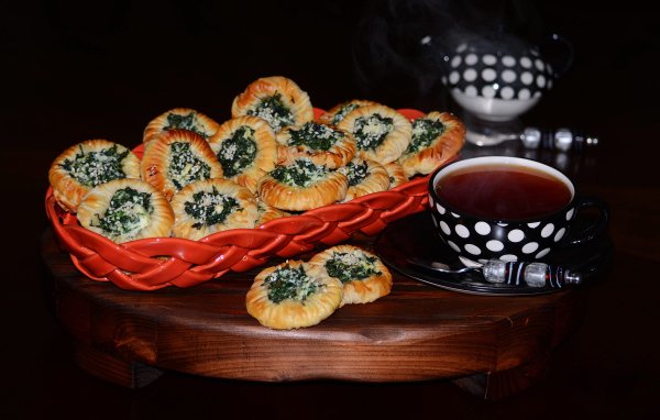 Булочки с зеленью и горячим чаем на черном фоне