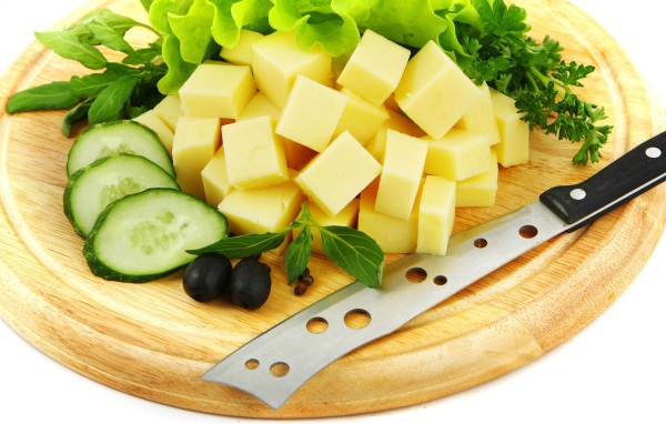 Сыр нарезанный кубиками на разделочной доске