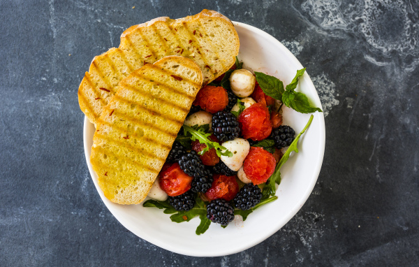 Гренки с салатом из ягод на белой тарелке