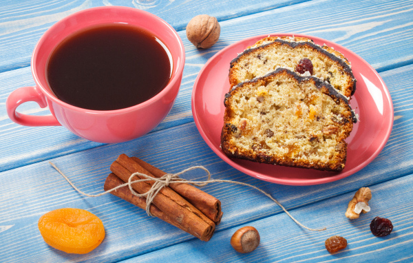 Кекс с корицей, орехами и курагой на столе с чашкой чая