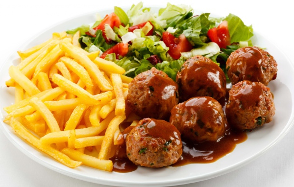 Картофель фри на белой тарелке с салатом и фрикадельками