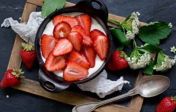 Свежая клубника с йогуртом на завтрак на столе с белым цветком