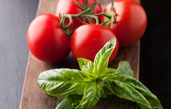 Свежие помидоры на разделочной с зеленью