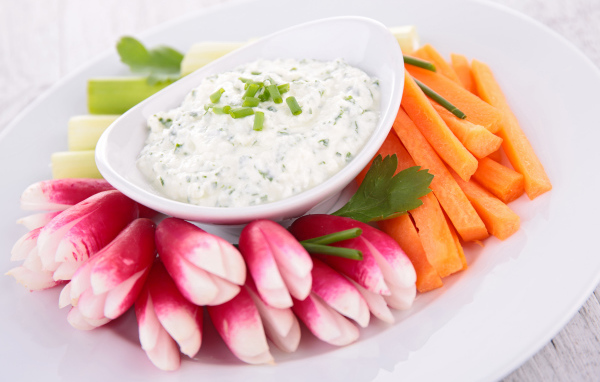 Свежие овощи с соусом в белой тарелке 