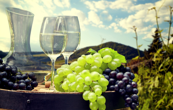 Гроздья синего и белого винограда с фужерами на деревянной бочке