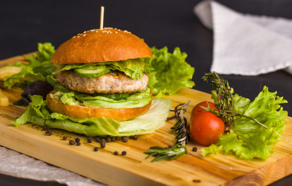 Гамбургер с зеленью на разделочной доске  