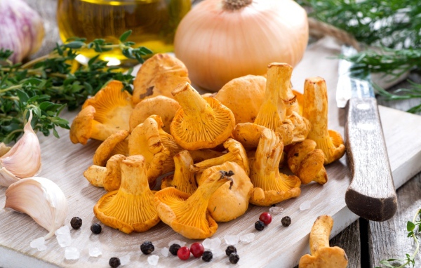 Грибы лисички и овощи на деревянной доске 