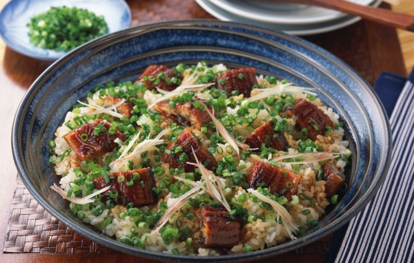 Рисовый плов с кусочками мяса и зеленым луком на столе