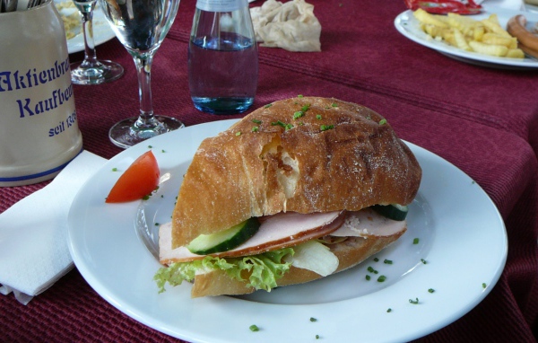 Сэндвич с ветчиной и овощами на столе в ресторане