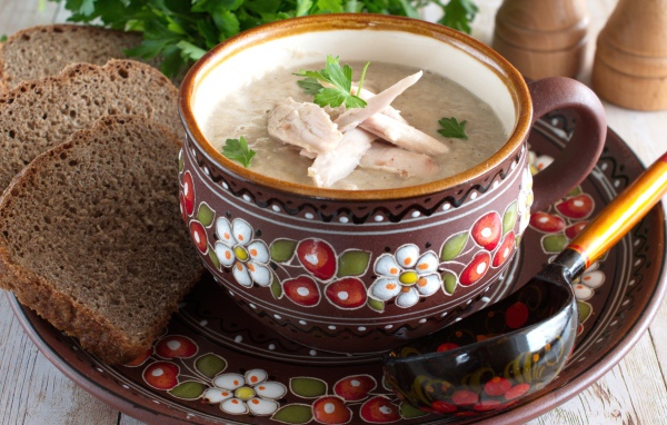 Суп с курицей в красивой тарелке на столе с черным хлебом