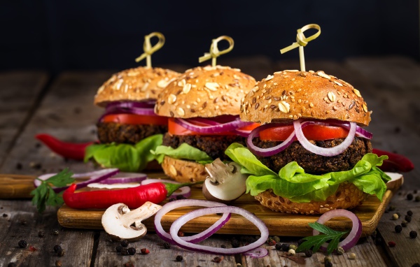 Три аппетитных гамбургера с кольцами лука и перцем