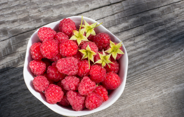 Аппетитная сочная свежая малина в белой тарелке 