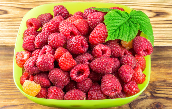 Свежая малина в зеленой миске на столе