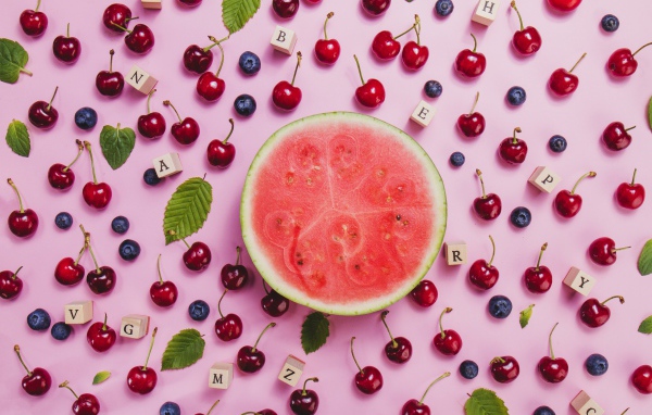 Половина арбуза с ягодами вишни и черники на столе