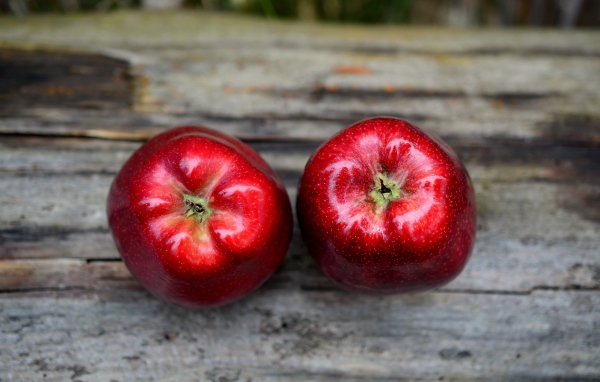 Два больших красных яблока на деревянном столе
