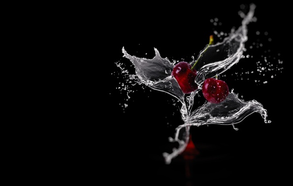 Две вишни в брызгах воды на черном фоне
