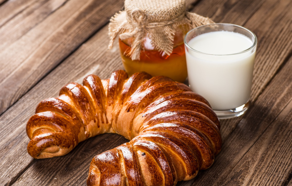 Свежая выпечка на столе с медом и стаканом молока