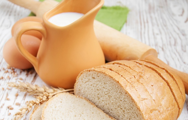 Белый нарезанный батон на столе с молоком