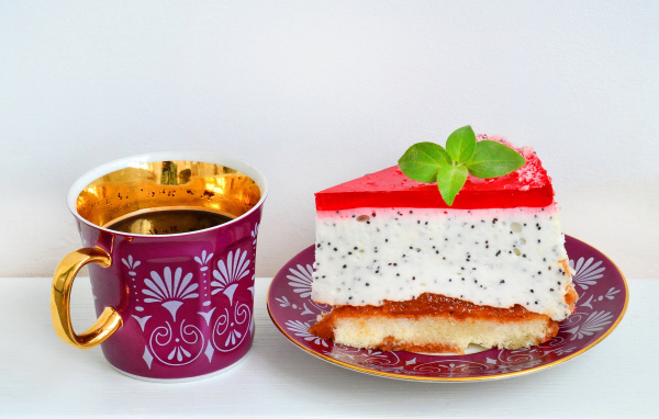 Кусок пирожного на тарелке с чашкой чая