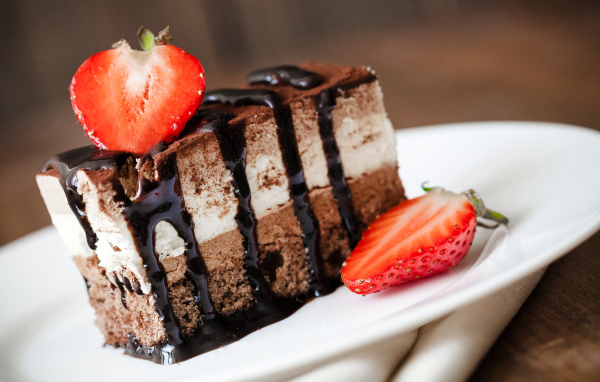 Кусок шоколадного пирожного со свежей клубникой