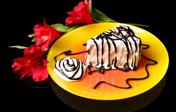 Аппетитное пирожное с шоколадом и цветком альстремерия на черном фоне