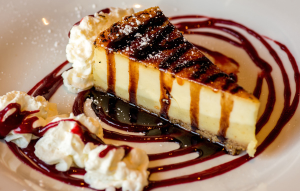 Аппетитный кусок чизкейка со сливками и клубничным джемом