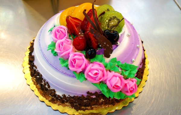 Красивый торт с фруктами украшен розовыми розами из крема