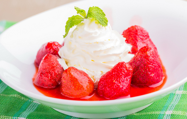 Вкусные сливки с клубникой на белой тарелке