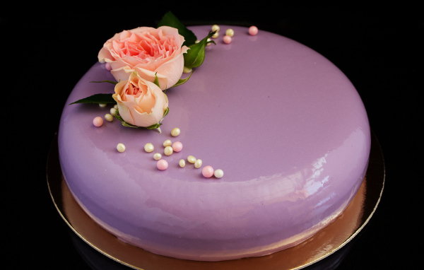 Глянцевый круглый фиолетовый торт с цветами розы на черном фоне