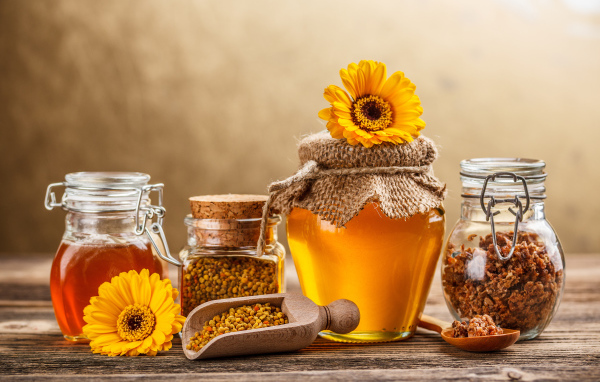Баночки с медом, пыльцой и прополисом на столе
